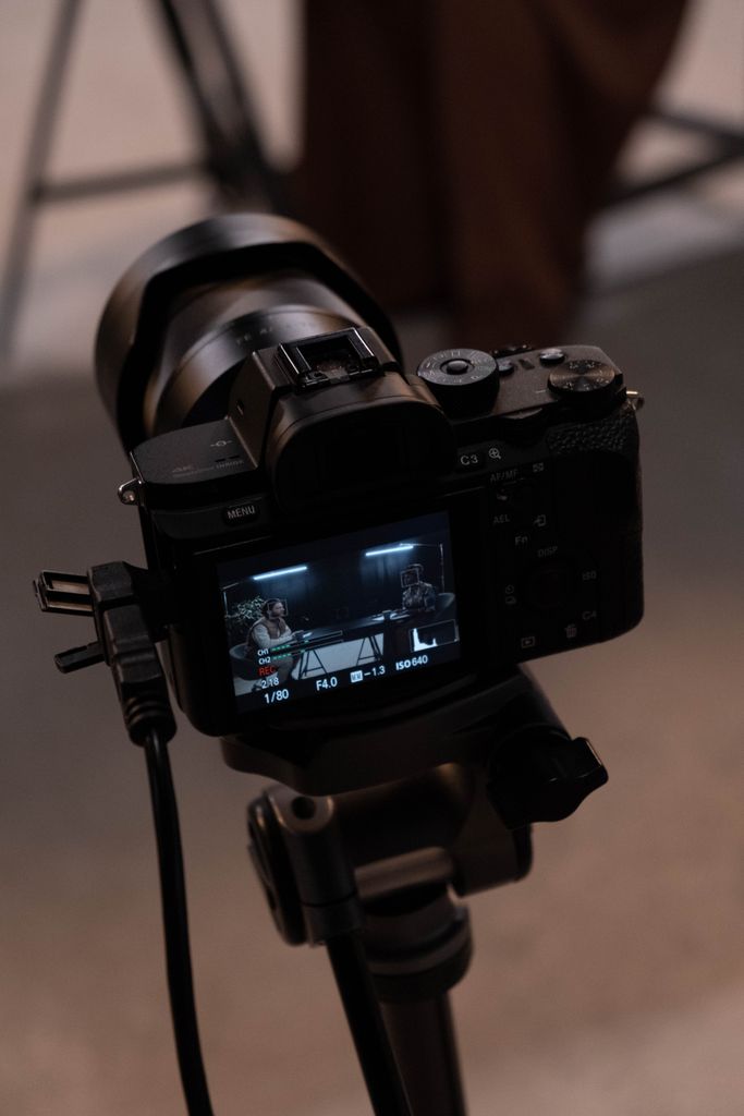 Close-up of a camera mounted on a tripod focused on a video production scene.