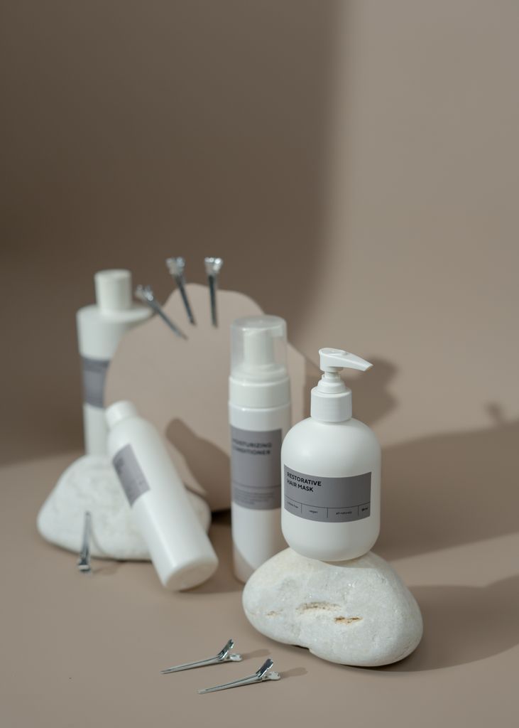 Minimalist display of cosmetic bottles with hair accessories on stones, ideal for beauty product promotion.